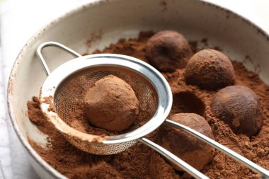 Işık masasında kakao tozuyla lezzetli çikolata şekerlemeleri yapmak, yakın plan.