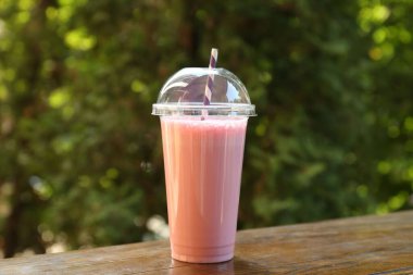 Dışarıdaki ahşap masada plastik bardakta lezzetli bir milkshake.