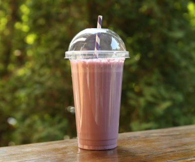 Dışarıdaki ahşap masada plastik bardakta lezzetli bir milkshake.
