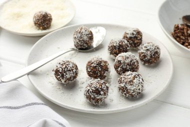 Beyaz ahşap masada fındıklı ve hindistan cevizli lezzetli çikolatalar, yakın plan.