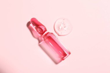 Pembe zemin üzerinde sıvı olan cam ampul, üst görünüm