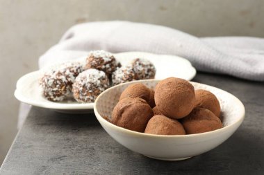 Gri masada kakao tozu, fındık ve hindistan cevizi taneleri olan lezzetli çikolata şekerleri, yakın plan.