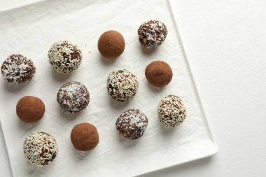 Beyaz masada kakao tozu, fındık ve susam tohumlu lezzetli çikolata şekerleri.