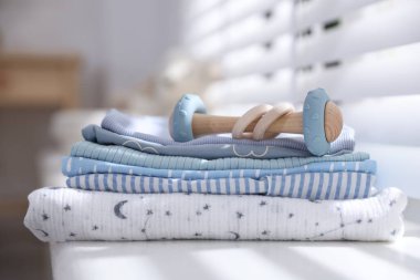 Temiz bebek kıyafetleri ve pencere pervazına aksesuar yığını.