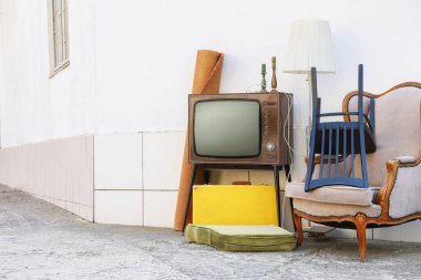 Tribünde Retro TV, koltuk ve beyaz duvarın yanında kullanılan diğer şeyler. Metin için boşluk