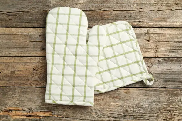 Fırın eldiveni ve tutacağı ahşap masanın üstünde, üst tarafta.