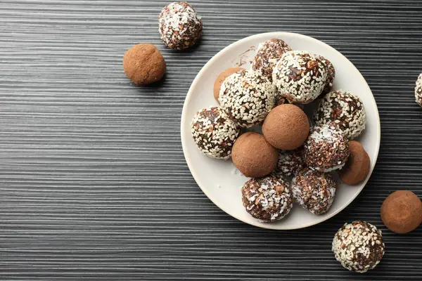 Kakao tozu, fındık ve susam tohumlu lezzetli çikolata şekerleri siyah desenli masa, düz yatak. Metin için boşluk