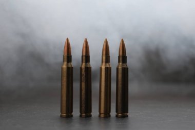 Gri masadaki ateşli silah fişekleri dumana karşı, yakın plan.