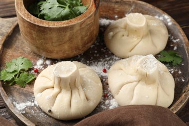 Ahşap masada biberli ve maydanozlu pişmemiş khinkaliler (hamur tatlısı), yakın plan.