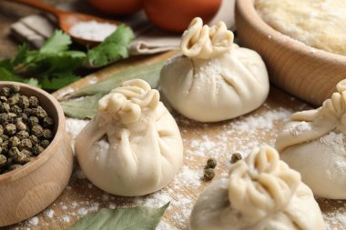 Biber, un ve defne yapraklarıyla pişirilmemiş khinkaliler (hamur köfteleri) ahşap masada, yakın plan