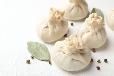 Biber ve defne yapraklarıyla pişirilmemiş khinkaliler (hamur tatlısı) beyaz masada, yakın plan.