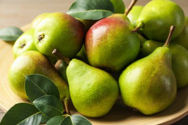 Taze armutlar ve yeşil yapraklar masada, yakın plan.