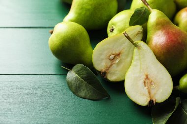 Taze armutlar ve yeşil ahşap masada yapraklar, yakın plan. Metin için boşluk