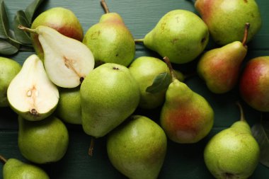 Taze olgun armutlar ve yeşil ahşap masa üzerinde yapraklar, düz uzanmış