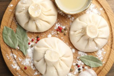 Biber, un ve defne yapraklarıyla ahşap masa üzerinde pişmemiş khinkaliler (hamur tatlısı)