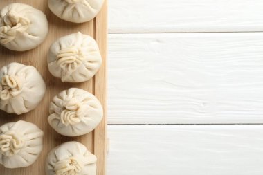 Beyaz ahşap masa üzerinde pişmemiş khinkaliler (hamur tatlısı), üst manzara. Metin için boşluk