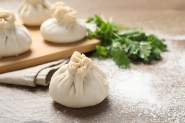 Ahşap masada pişmemiş khinkaliler (hamur tatlısı) ve kişniş, yakın plan. Metin için boşluk