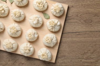 Pişmemiş khinkalis (hamur tatlısı) ve defne yaprakları ahşap masa üzerinde, üst manzara. Metin için boşluk