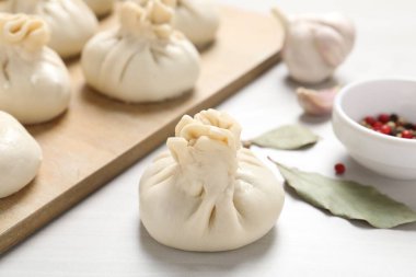 Pişmemiş khinkaliler (hamur tatlısı) ve beyaz ahşap masa üzerindeki baharatlar, yakın plan.