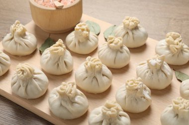 Ahşap masada pişmemiş khinkaliler (hamur tatlısı) ve baharatlar, yakın plan.