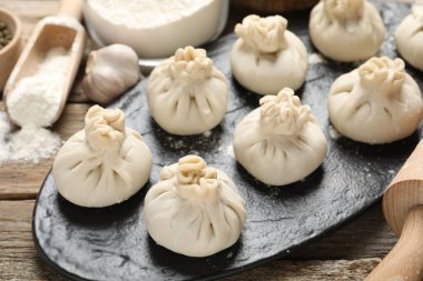 Pişmemiş khinkaliler (hamur tatlısı), un, sarımsak ve yuvarlak raptiye, ahşap masa, yakın plan