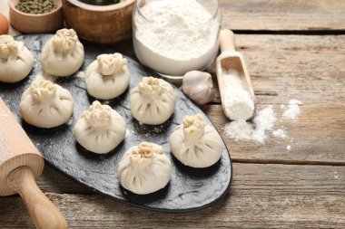 Pişmemiş khinkaliler (hamur tatlısı), un, baharatlar ve ahşap masa üzerinde merdane, yakın plan. Metin için boşluk