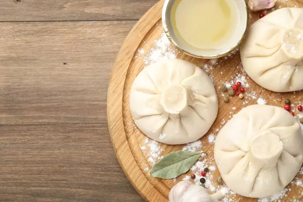 Biber, un ve defne yapraklarıyla ahşap masa üzerinde pişmemiş khinkaliler (hamur köfteleri). Metin için boşluk