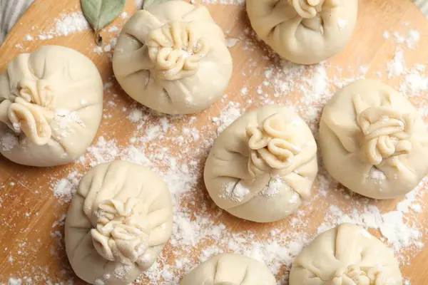 Tahta üzerinde un olan pişmemiş khinkaliler (hamur tatlısı), üst manzara