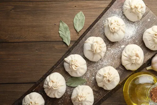 Tahta masa üzerinde un, sarımsak ve defne yapraklarıyla pişirilmemiş khinkaliler (hamur tatlısı)