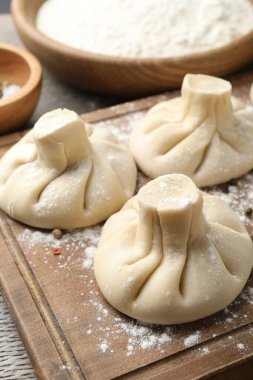 Ahşap masada pişmemiş khinkaliler (hamur tatlısı), yakın plan.