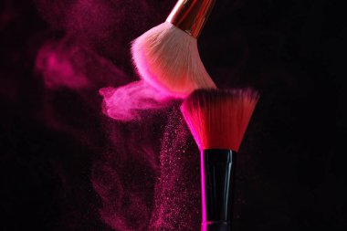 Siyah arka planda neon ışıklarda pembe göz farlı makyaj fırçaları, yakın plan