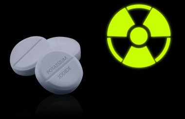 Potasyum iyodür hapları ve siyah arka planda uyarı işareti. Radyoaktif kirlenme sırasında iyot tüketimi