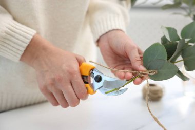 Çiçekçi çiçekçide okaliptüs dallarından güzel bir buket yapıyor, yakın plan.