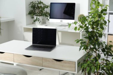 Dizüstü bilgisayarı, modern bilgisayarı ve çiçek dekoru olan şık bir iş yeri. Biyofilik iç tasarım