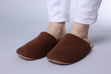 Gri arka planda yumuşak kahverengi terlikli kadın, yakın plan.