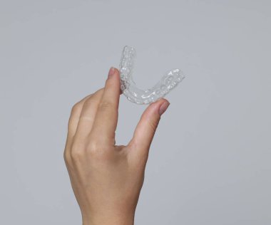 Gri arka planda diş hizalayan kadın, yakın plan.