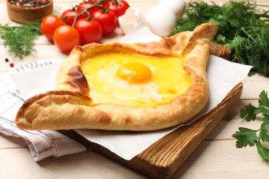 Tahta masada servis edilen peynirli ve yumurtalı leziz khachapuri.