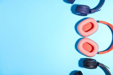 Açık mavi arka planda farklı tarz kulaklıklar, düz yatış. Metin için boşluk