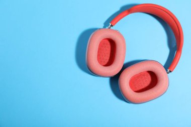 Açık mavi arka planda bir çift şık pembe kulaklık, üst manzara. Metin için boşluk