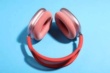 Açık mavi arka planda bir çift şık pembe kulaklık.