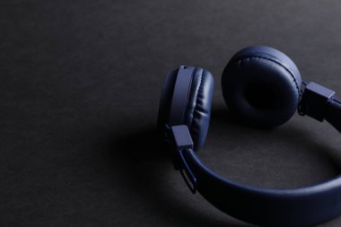 Siyah arka planda bir çift şık mavi kulaklık, yakın plan. Metin için boşluk