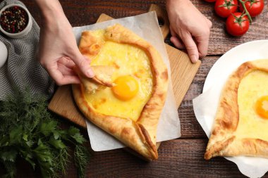 Ahşap masada nefis khachapuri yiyen bir kadın.