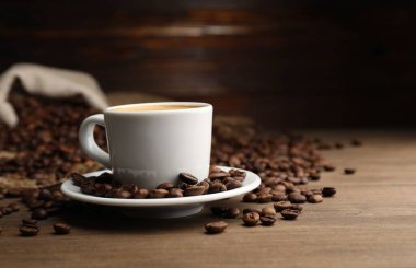 Aromatik kahve fincanda, fasulye de ahşap masada, yakın plan. Metin için boşluk