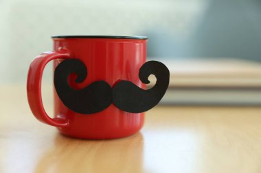 Babalar Günün kutlu olsun. Bıyıklı kupa ve defterler kapalı masa üzerinde, yakın plan. Metin için boşluk