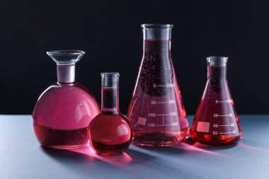 Siyah zemin üzerinde kırmızı sıvı bulunan laboratuvar camları