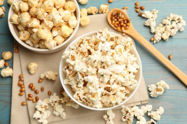 Lezzetli patlamış mısır ve mısır taneleri açık mavi ahşap masa, düz uzanmış