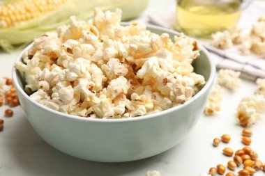 Lezzetli patlamış mısır ve mısır taneleri beyaz mermer masada, yakın plan.