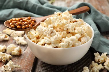 Tahta masada lezzetli patlamış mısır ve mısır taneleri, yakın plan.