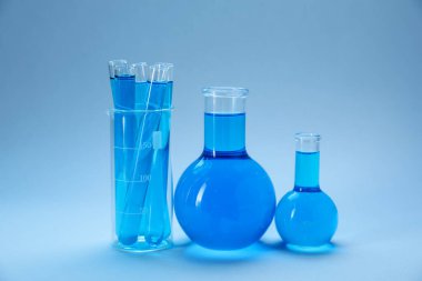 Açık mavi gradyan üzerinde parlak sıvı bulunan farklı bir laboratuvar camı.