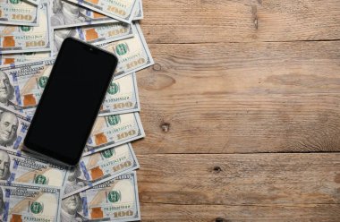 Akıllı telefon ve para ahşap masada, düz yerde. Metin için boşluk